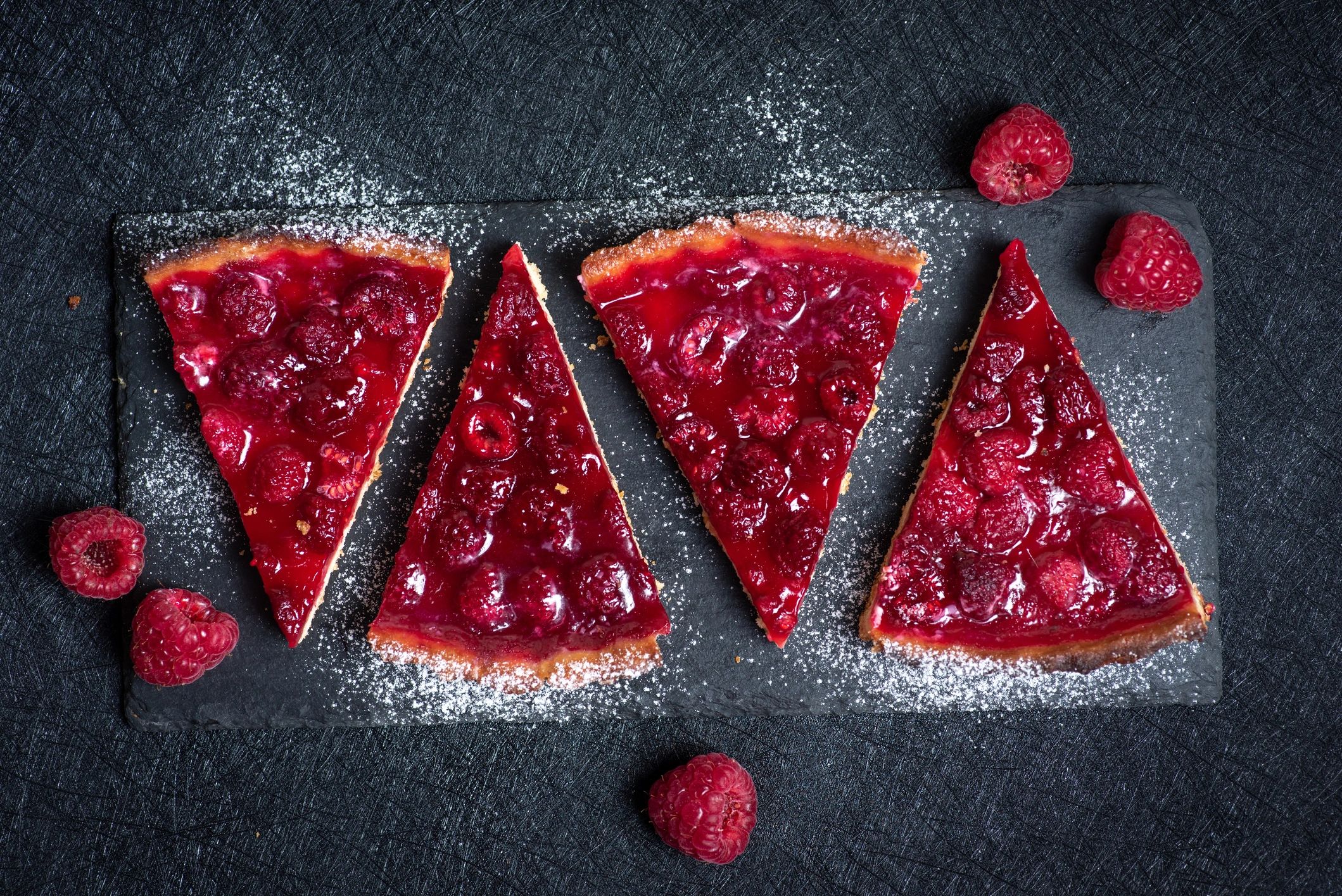 Slices of tart topped with fresh raspberries